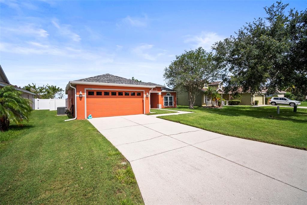 A single-story house with an orange exterior and a two-car garage sits on a lawn — 4194 BANBURY CIRCLE, PARRISH, FL