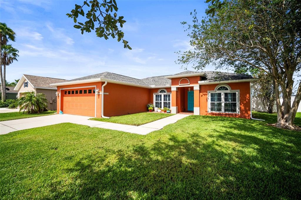 A single-story house with orange stucco walls, a two-car garage, and a front walkway — 4194 BANBURY CIRCLE, PARRISH, FL