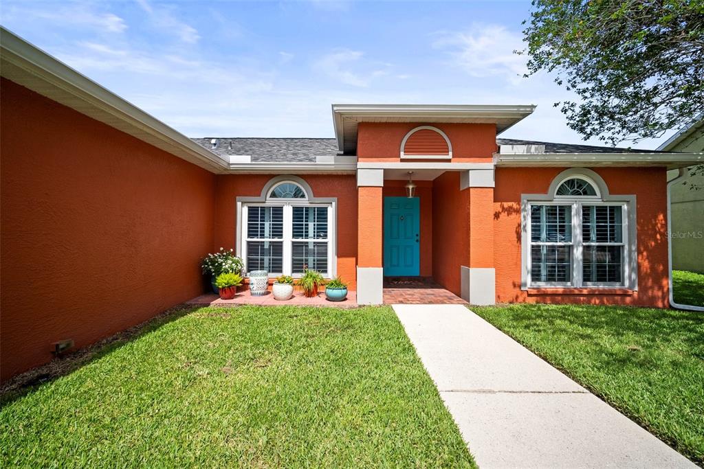 A single-story house with orange stucco walls, a bright blue front door, and a walkway — 4194 BANBURY CIRCLE, PARRISH, FL