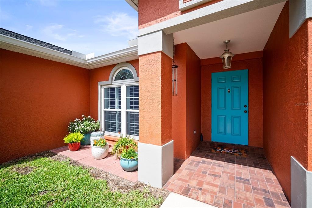A bright blue front door sits under a covered entryway with orange stucco walls — 4194 BANBURY CIRCLE, PARRISH, FL