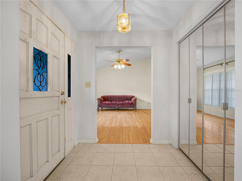 An entryway with tiled floors, a white front door, and mirrored closet doors leads inside — 6050 LUNN ROAD, LAKELAND, FL