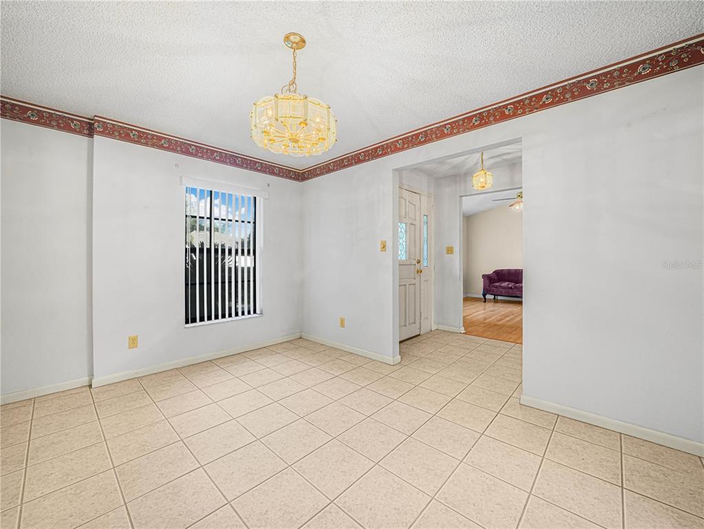 A dining room with tile flooring, a chandelier, and a floral wallpaper border — 6050 LUNN ROAD, LAKELAND, FL