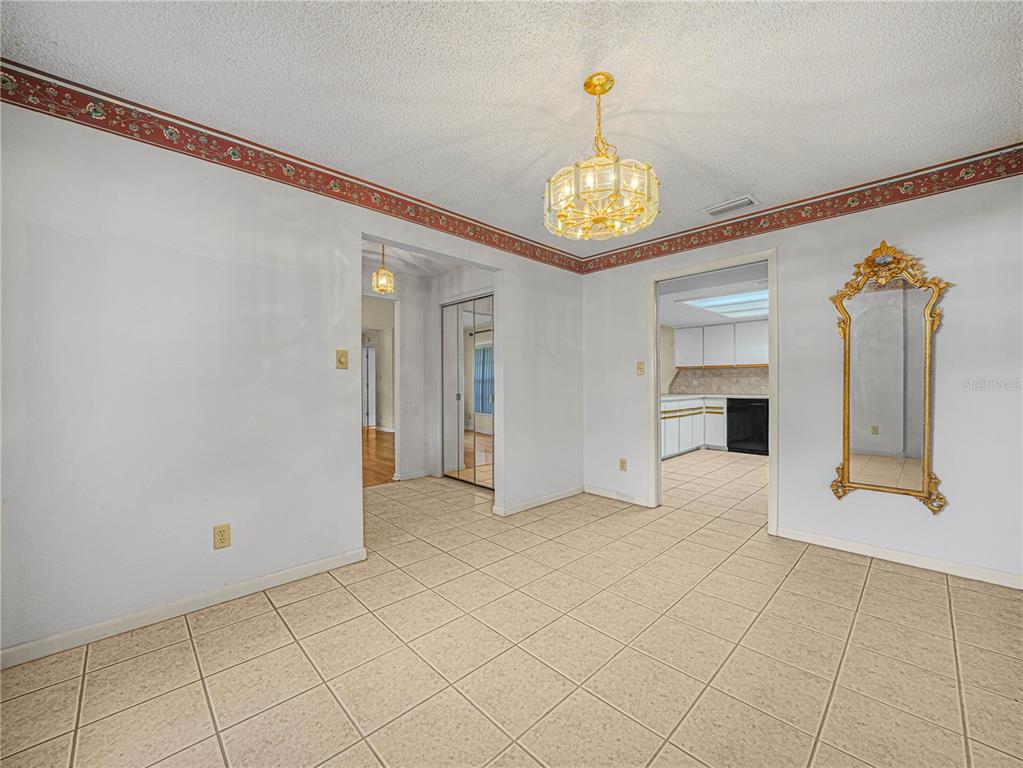 A dining area with tile flooring, a gold chandelier, and a decorative wall mirror — 6050 LUNN ROAD, LAKELAND, FL