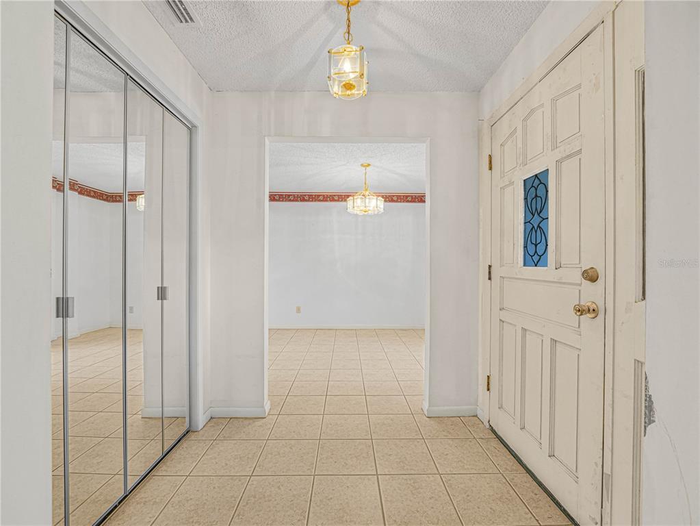 An entryway features tiled floors, a mirrored closet, a white front door, and two light fixtures — 6050 LUNN ROAD, LAKELAND, FL
