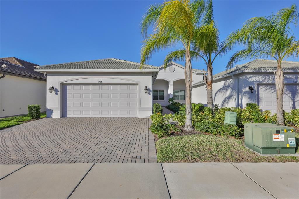 A single-story house with a paved driveway, a two-car garage, and a palm tree — 4906 AVILA LAKES DRIVE, WIMAUMA, FL