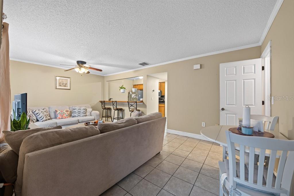 A living room with tile flooring, a breakfast bar, and a sofa facing a television — 1409 ALPINE ROAD UNIT 10, CLEARWATER, FL