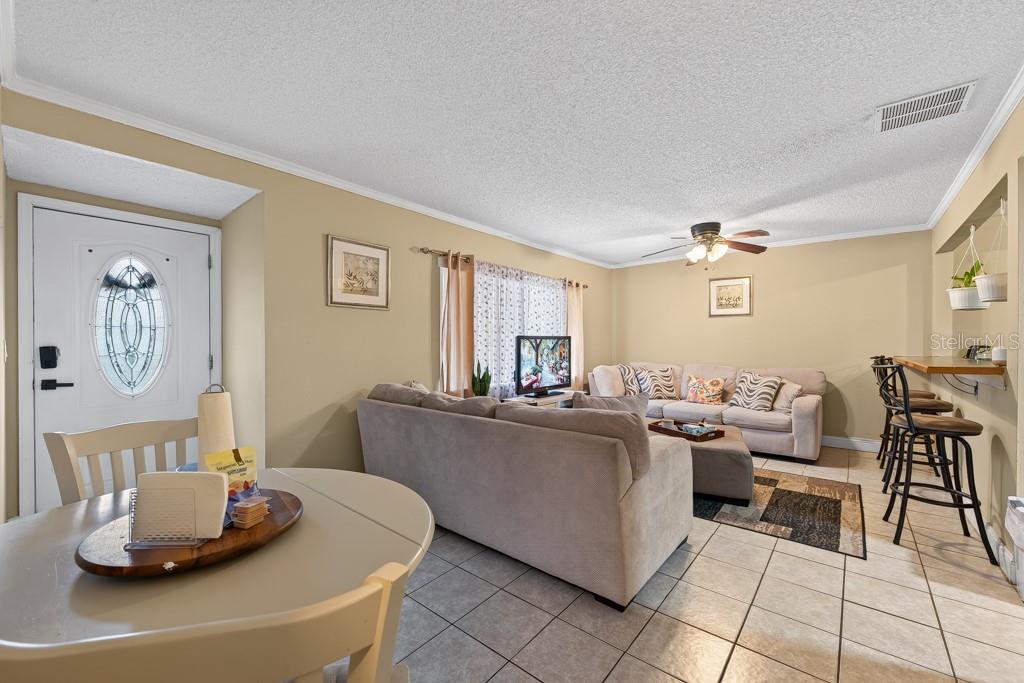 A living room with tile floors, a sectional sofa, a dining table, and a breakfast bar — 1409 ALPINE ROAD UNIT 10, CLEARWATER, FL