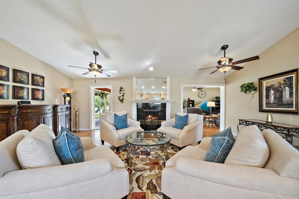 A living room features a fireplace, two ceiling fans, and four beige armchairs — 4352 KINGSTON LOOP, SARASOTA, FL