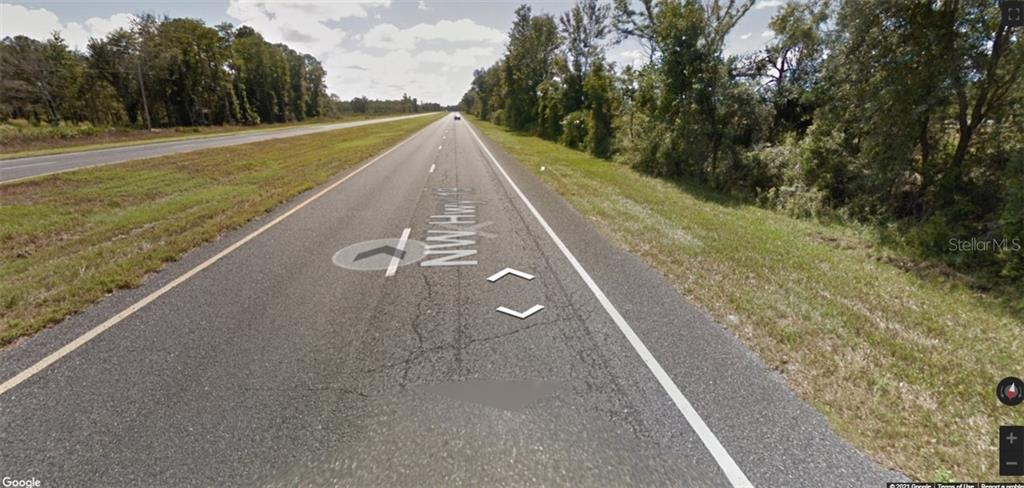 A view of a two-lane asphalt road surrounded by trees and grassy shoulders — SW 316TH AVENUE, CROSS CITY, FL