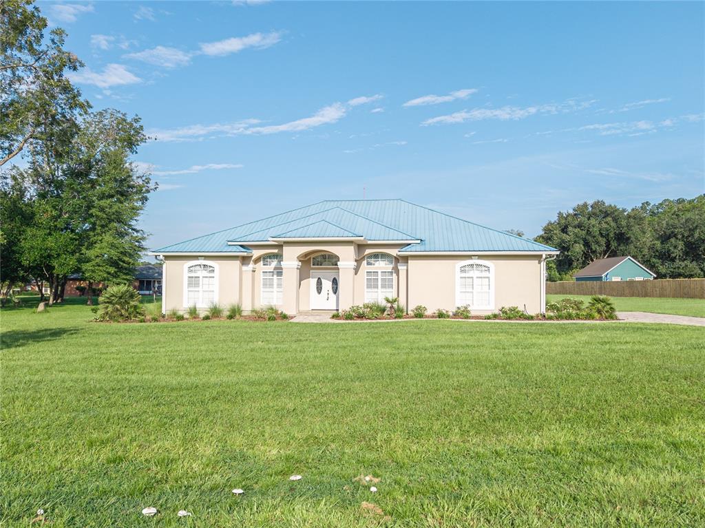 A single-story house with a blue metal roof sits on a grassy lot — 254 SW NIGHTSHADE DRIVE, LAKE CITY, FL
