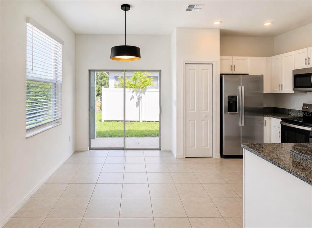 A dining area with tile floors, a pendant light, and a sliding door to the backyard — 10268 HONEY HAMMOCK WAY, SAN ANTONIO, FL