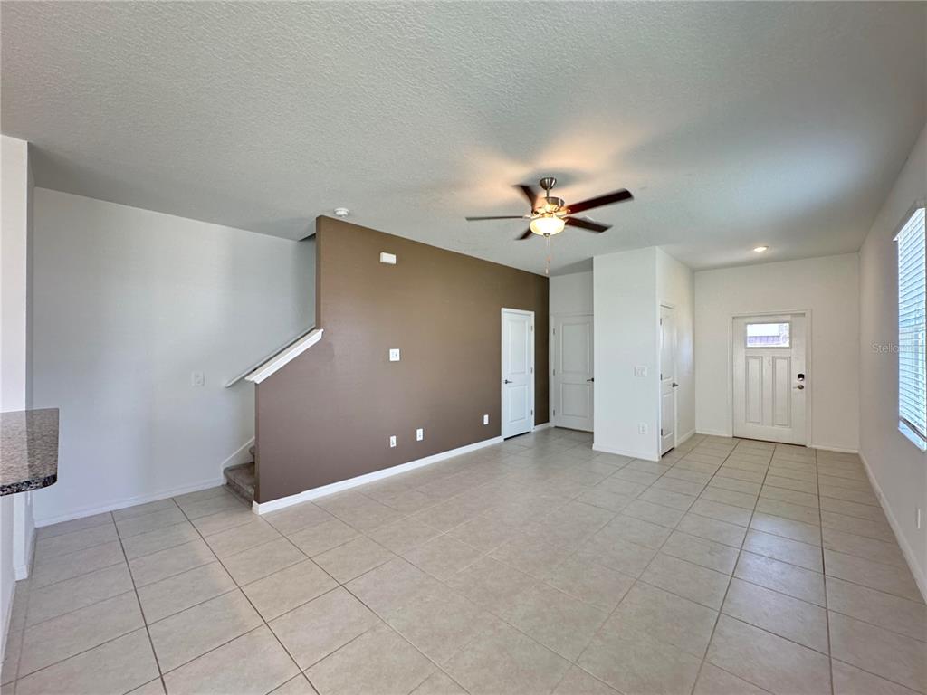 An open living area features tan tile flooring, a brown accent wall, and a ceiling fan — 10268 HONEY HAMMOCK WAY, SAN ANTONIO, FL
