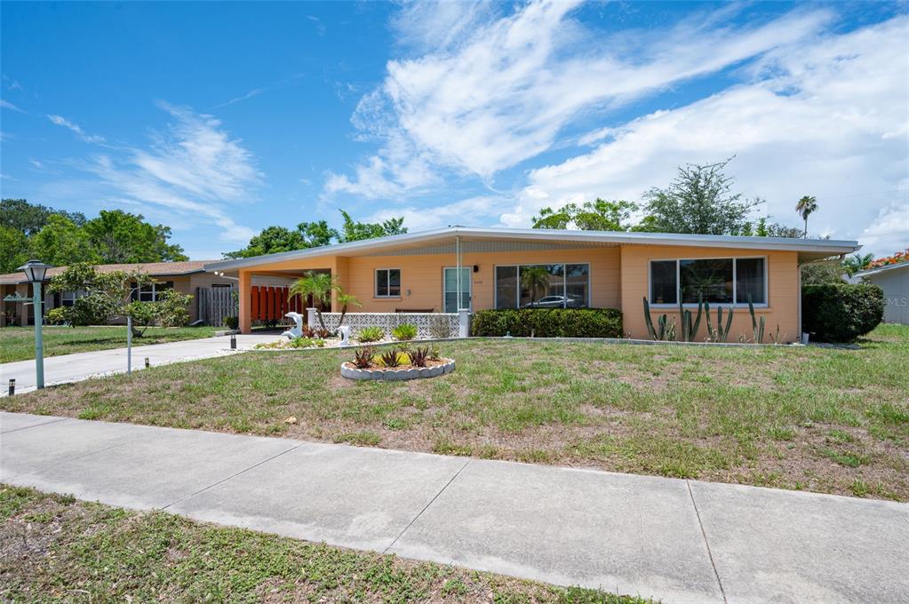 A single-story peach-colored house features a flat roof, a carport, and a front lawn — 2215 GROVE STREET, SARASOTA, FL