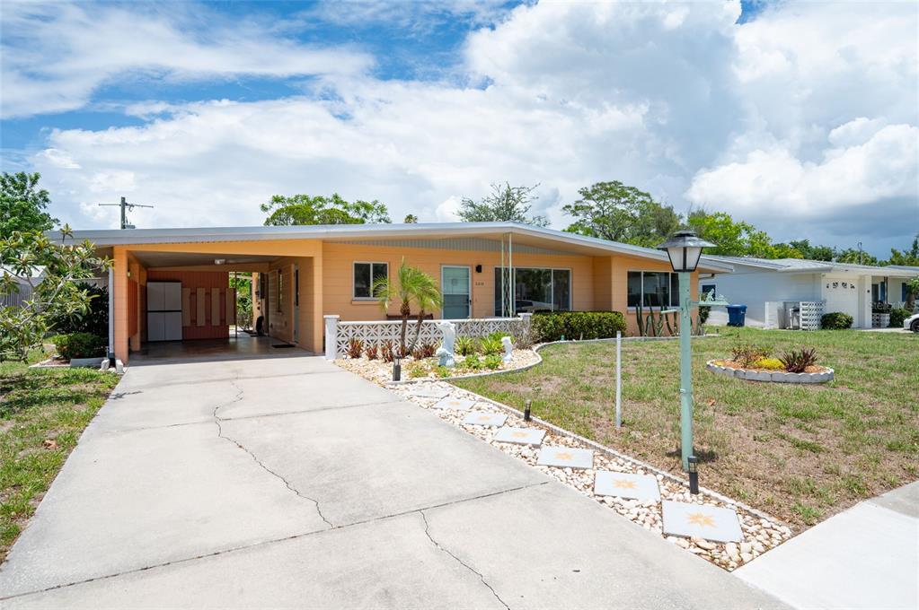 A single-story house with a carport, concrete driveway, and a small front yard — 2215 GROVE STREET, SARASOTA, FL