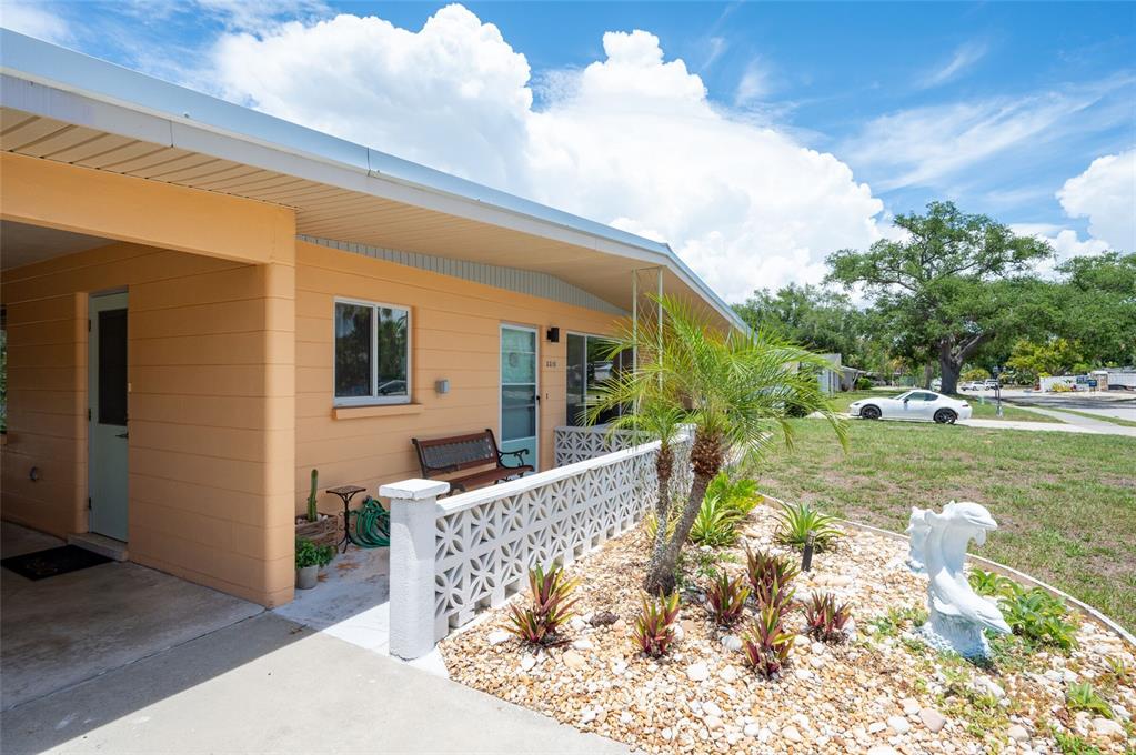 A peach-colored house exterior features a covered carport, a small patio, and a decorative screen — 2215 GROVE STREET, SARASOTA, FL