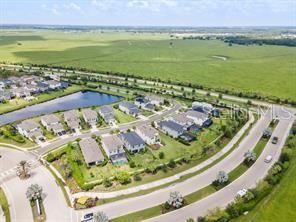 An aerial view shows a suburban neighborhood with houses, a pond, and surrounding green fields — 8370 VELDA TRAIL, SARASOTA, FL