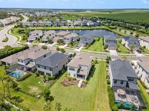 An aerial view shows a suburban neighborhood with houses, a central pond, and green lawns — 8370 VELDA TRAIL, SARASOTA, FL