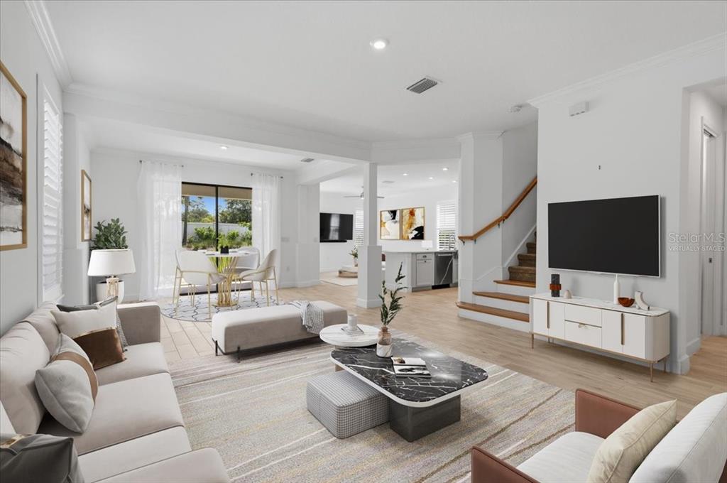 This virtually staged living room features light wood flooring, a staircase, and an open layout — 8370 VELDA TRAIL, SARASOTA, FL