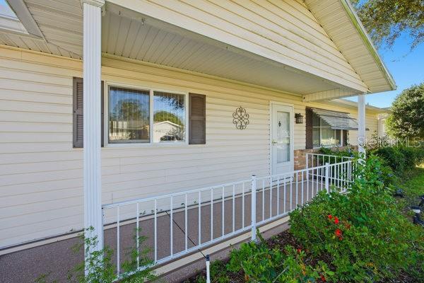A beige house exterior features a covered front porch with a white metal railing — 17831 SE 96TH AVENUE, SUMMERFIELD, FL