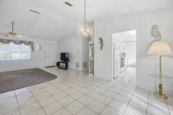 A bright living and dining area features white tile floors, a ceiling fan, and chandelier — 17831 SE 96TH AVENUE, SUMMERFIELD, FL