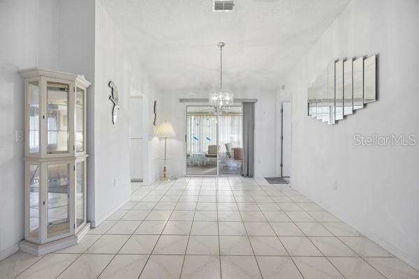 A bright dining room features white tile floors, a crystal chandelier, and a glass display cabinet — 17831 SE 96TH AVENUE, SUMMERFIELD, FL