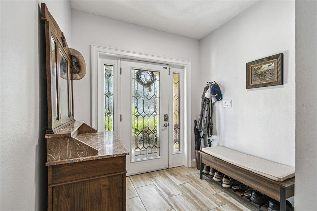 An entryway features a staircase, wood-look tile flooring, a bench, and framed wall art — 6331 SUNSET BAY CIRCLE, APOLLO BEACH, FL