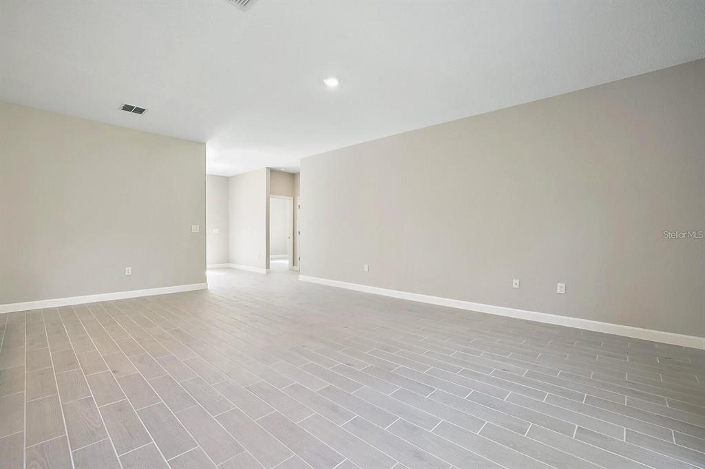 An empty room features light gray wood-look tile flooring and neutral painted walls — 5454 RHAPSODY AVENUE, NORTH PORT, FL