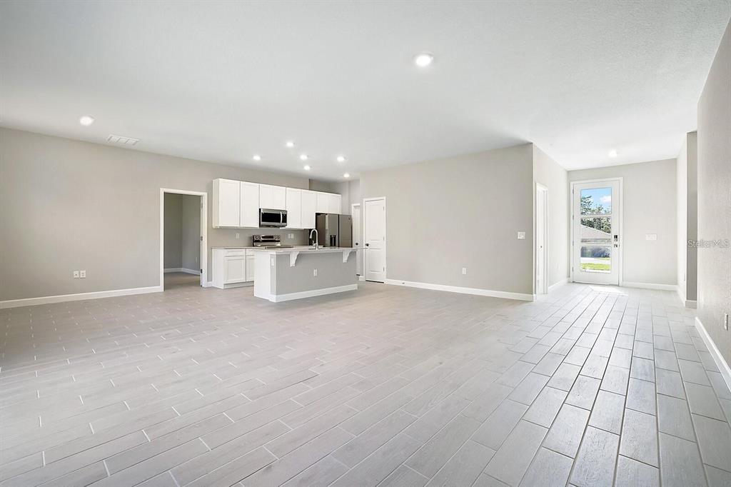 An open-concept kitchen and living area features white cabinetry, a center island, and light-colored flooring — 5454 RHAPSODY AVENUE, NORTH PORT, FL
