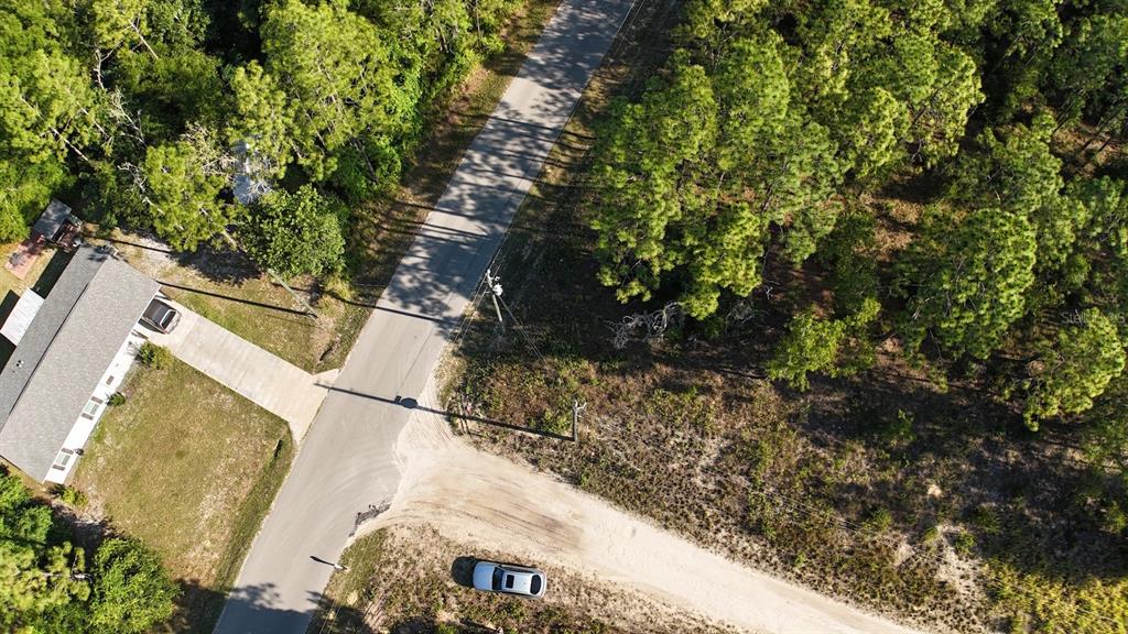 An aerial view shows a house, a paved road, and a wooded lot with a car — SW 38th Street & SW 159 COURT, OCALA, FL