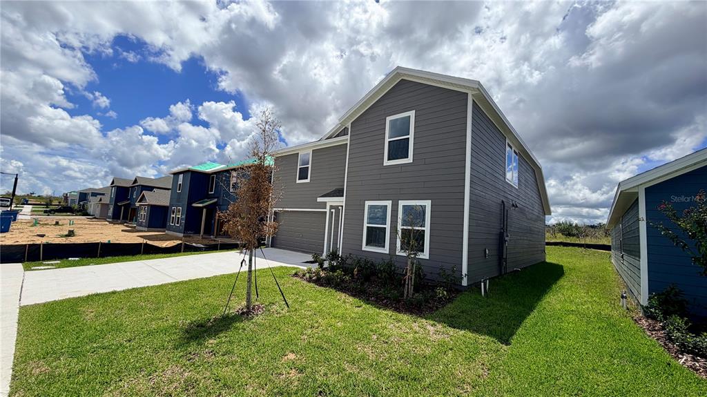 A two-story gray house with a garage and a concrete driveway under a cloudy sky — 583 ARTEMIS STREET, LAKE WALES, FL