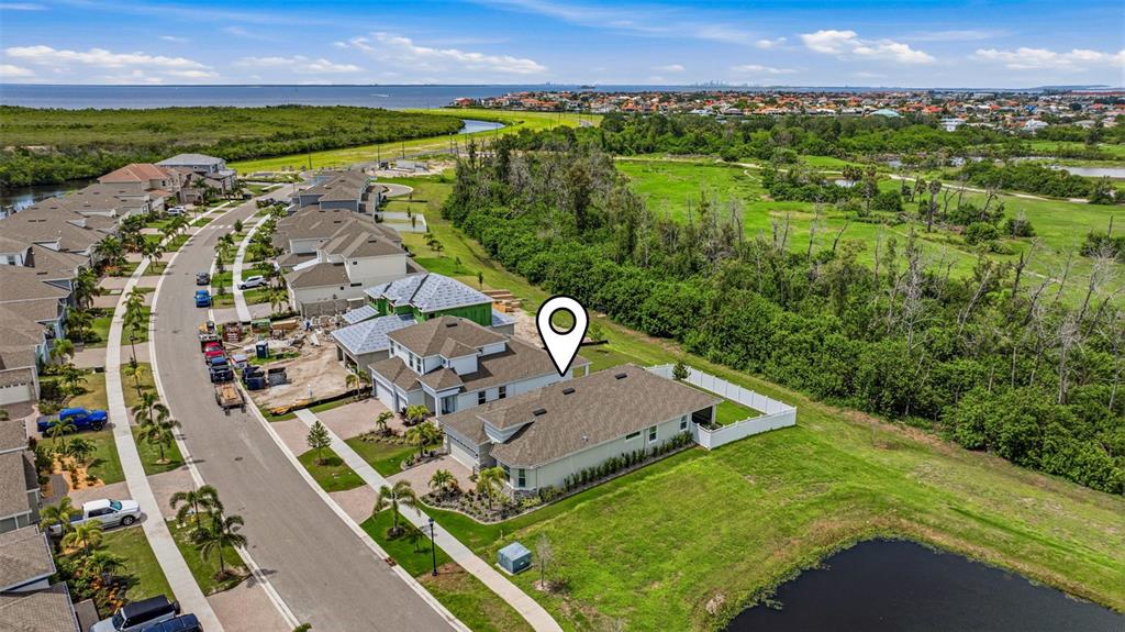 An aerial view shows a suburban house with a white fence bordering a small pond — 1065 SIGNET DRIVE, APOLLO BEACH, FL
