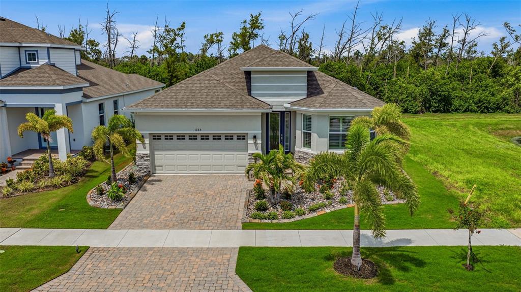 A single-story house with a paved driveway, a two-car garage, and palm trees in front — 1065 SIGNET DRIVE, APOLLO BEACH, FL