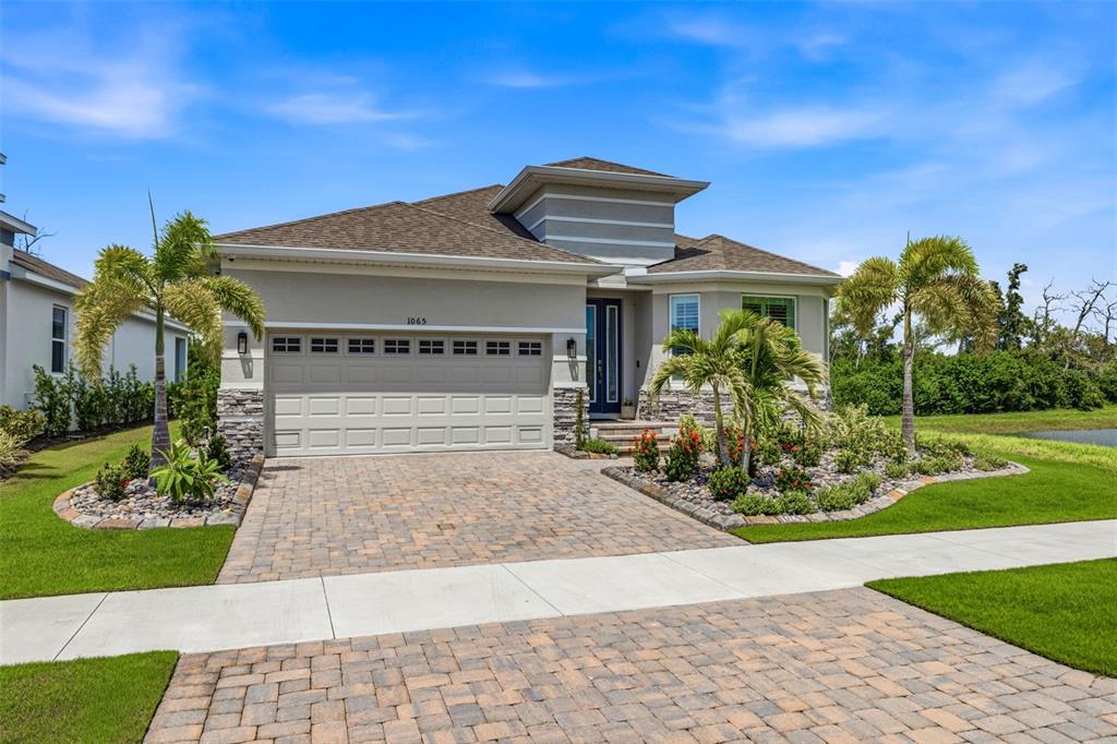 A single-story house with a paved driveway, stone accents, and palm trees in the front yard — 1065 SIGNET DRIVE, APOLLO BEACH, FL