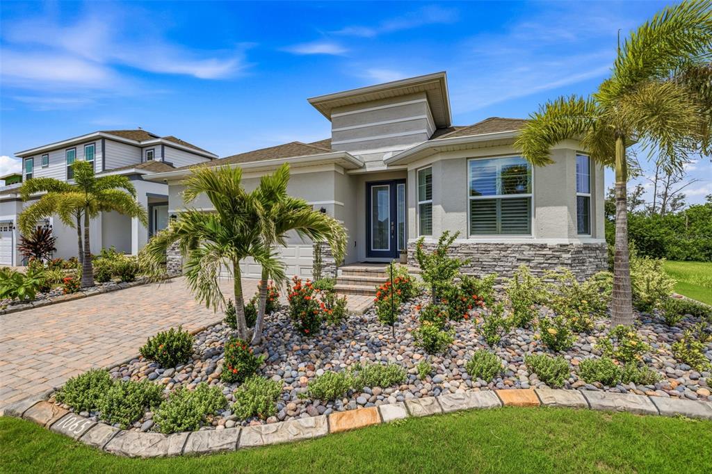 A single-story house with a stone facade, a paved driveway, and palm trees in the yard — 1065 SIGNET DRIVE, APOLLO BEACH, FL