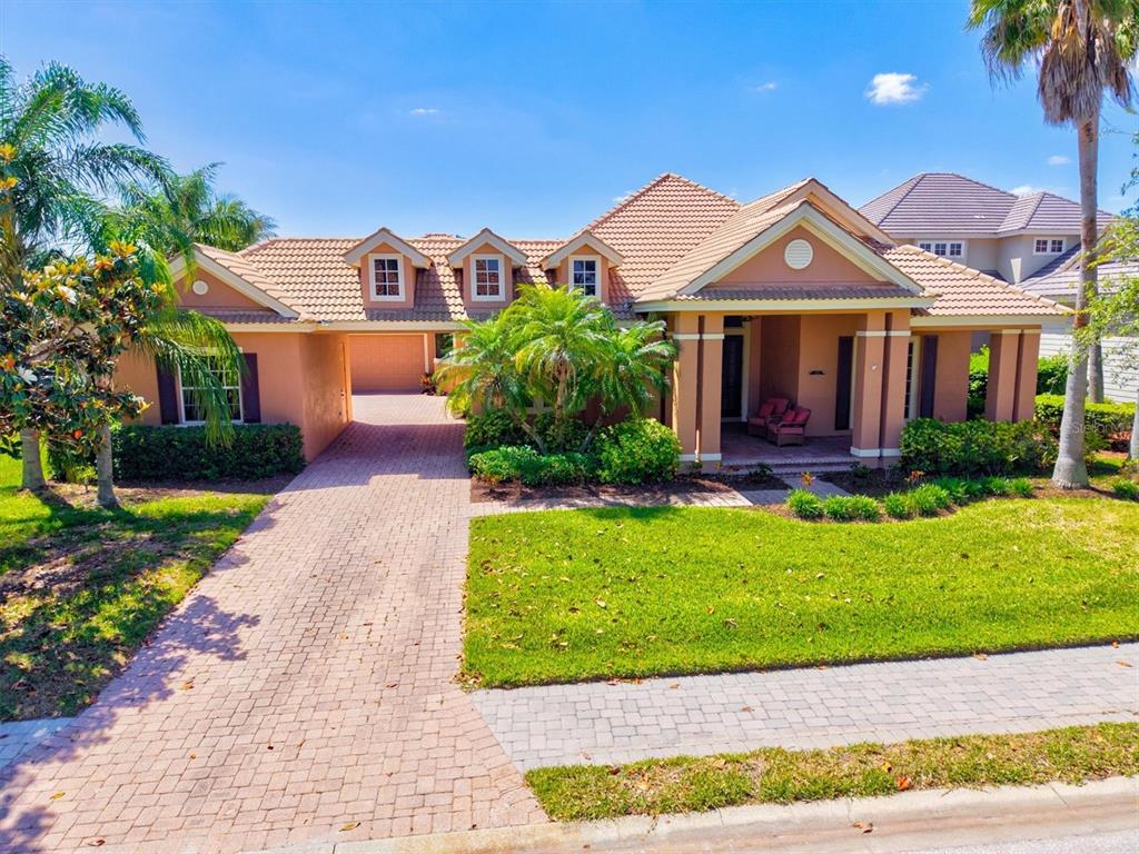 A single-story house with a tiled roof, a brick driveway, and a covered front porch — 4714 MAINSAIL DRIVE, BRADENTON, FL