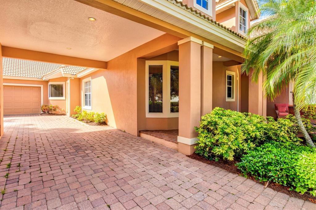 A paved driveway leads to the covered entrance and garage of a tan stucco house — 4714 MAINSAIL DRIVE, BRADENTON, FL