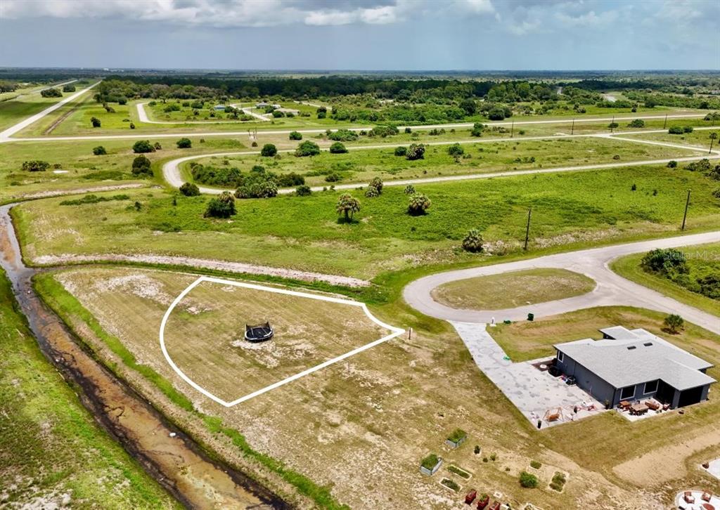 An aerial view shows a vacant, outlined residential lot next to a house and canal — 218 LYNBROOK LOOP, LABELLE, FL