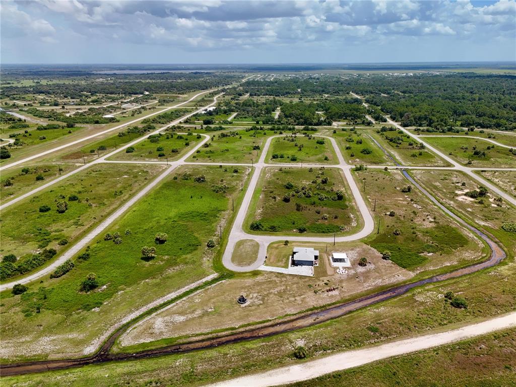 An aerial view shows a single house on a large, undeveloped lot with dirt roads — 218 LYNBROOK LOOP, LABELLE, FL