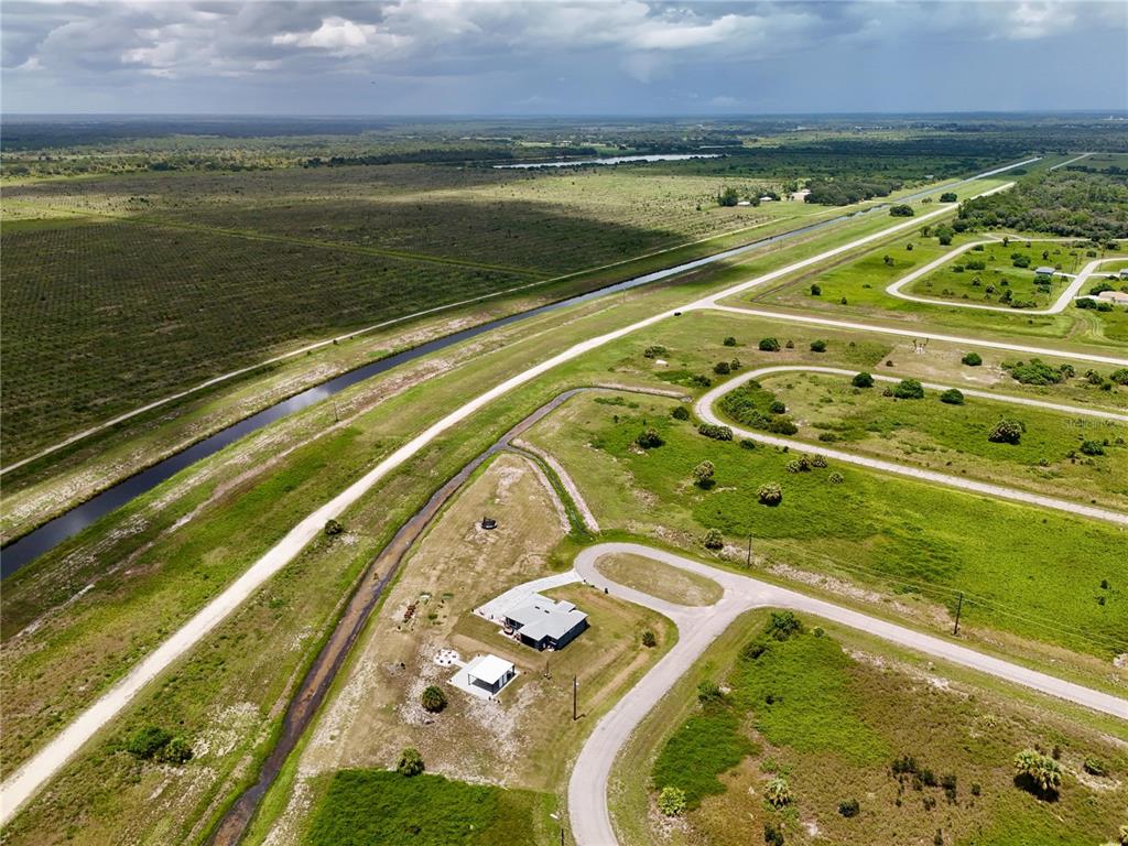 An aerial view shows a house with a detached garage on a rural, grassy lot — 218 LYNBROOK LOOP, LABELLE, FL