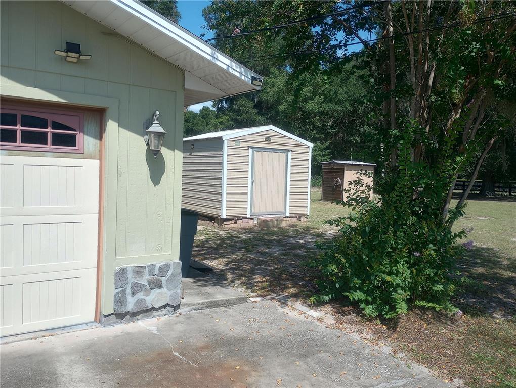 A light green garage exterior with a metal storage shed in the backyard — 13300 NE 38TH AVENUE, ANTHONY, FL