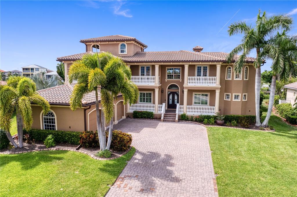A large, two-story tan house with a tiled roof, white balconies, and a paved driveway — 6459 RUBIA CIRCLE, APOLLO BEACH, FL