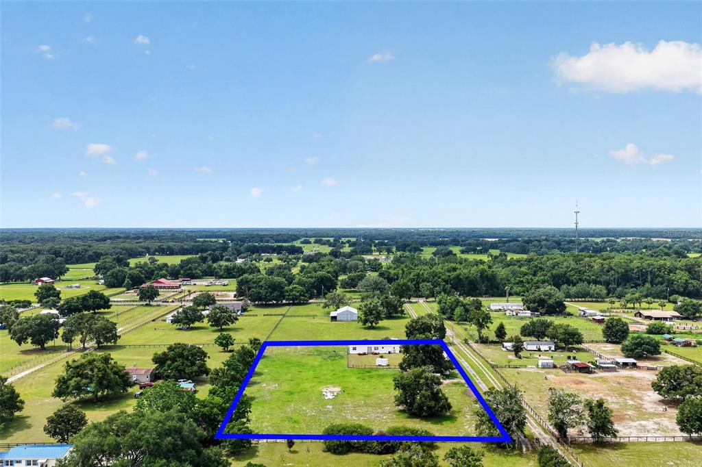 An aerial view shows a rectangular plot of land outlined in blue with a house — 311 SE HIGHWAY 42, SUMMERFIELD, FL
