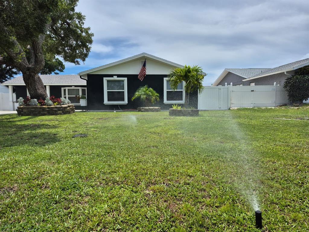 A dark-painted single-story house with a concrete driveway lined with blue solar lights — 5817 TAMPA SHORES BOULEVARD, TAMPA, FL