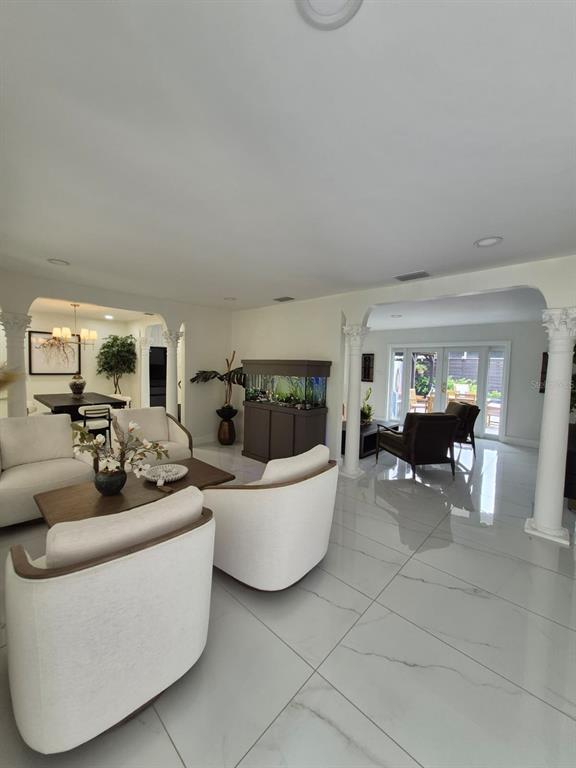 A living room features white marble-look tile flooring, a brown leather sofa, and two armchairs — 5817 TAMPA SHORES BOULEVARD, TAMPA, FL