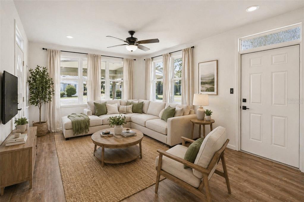 A living room features a sectional sofa, round coffee table, armchair, and light wood flooring — 822 POINSETTIA DRIVE, EUSTIS, FL