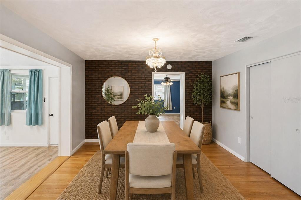 A dining room features a dark brick accent wall, a wooden table, and a chandelier — 822 POINSETTIA DRIVE, EUSTIS, FL