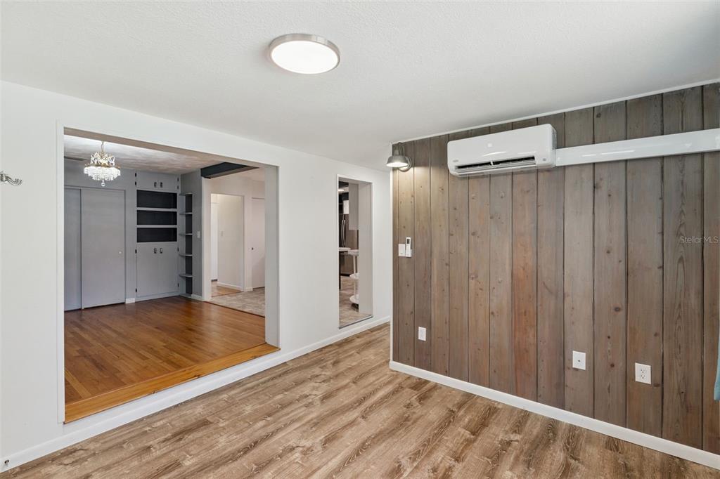 A room with wood-look flooring, a wood-paneled accent wall, and a wall-mounted air conditioning unit — 822 POINSETTIA DRIVE, EUSTIS, FL