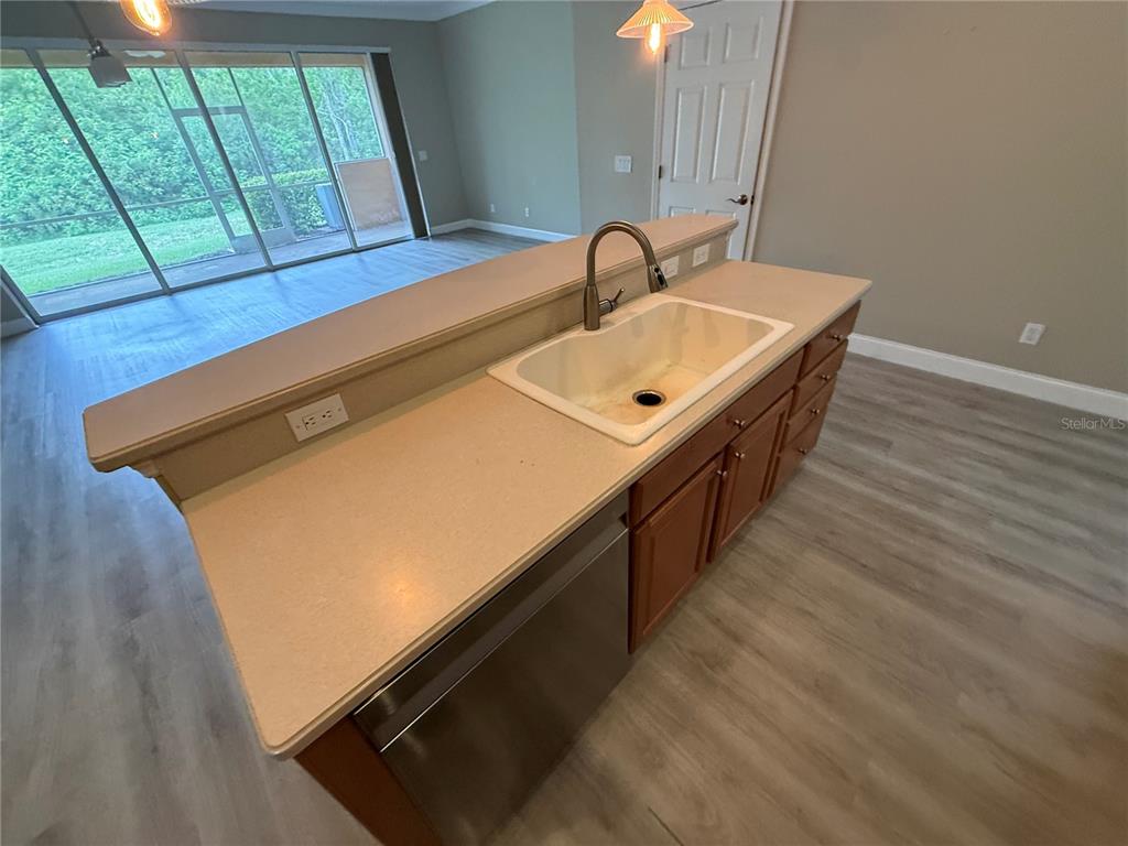 A kitchen island with a stainless steel dishwasher, sink, and beige countertops — 11550 52ND COURT E, PARRISH, FL