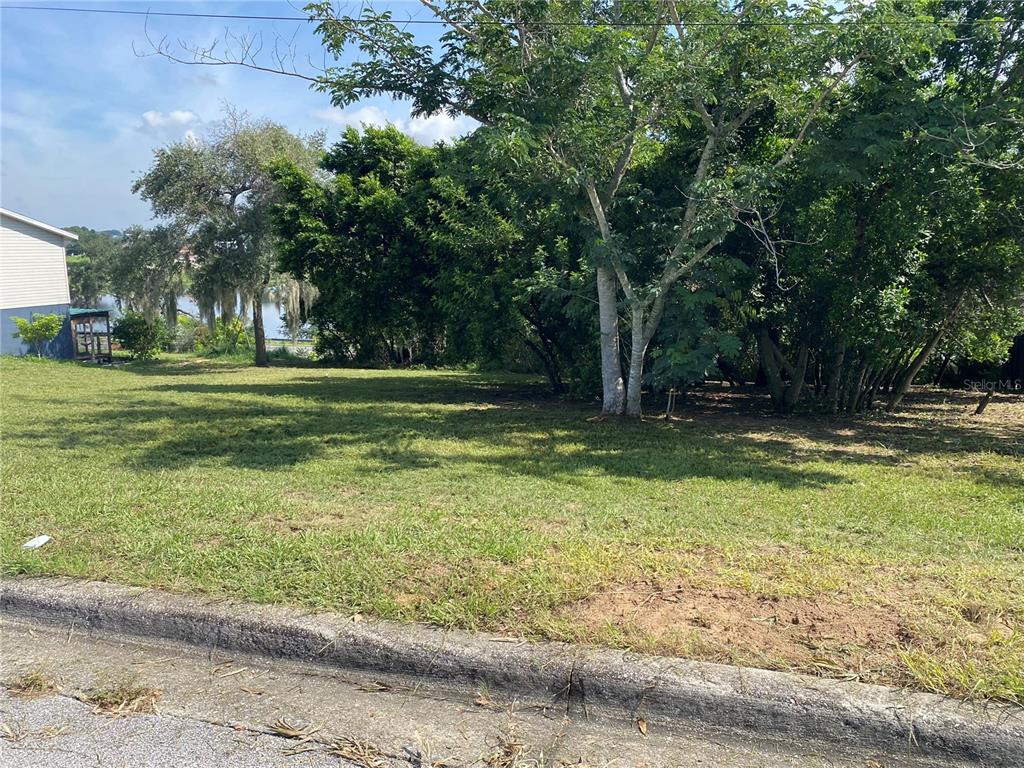 A grassy, vacant residential lot features mature trees and a view of a distant lake — LAKEVIEW AVENUE, DUNDEE, FL