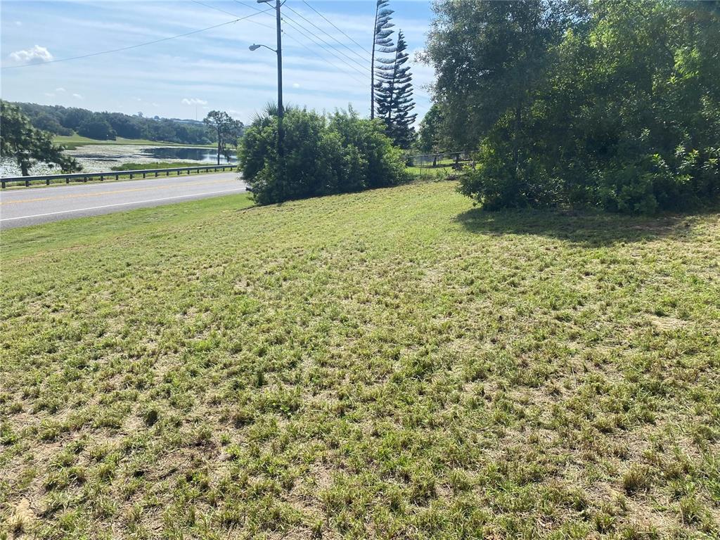 A grassy, sloped lot sits beside a road with a lake visible in the distance — LAKEVIEW AVENUE, DUNDEE, FL